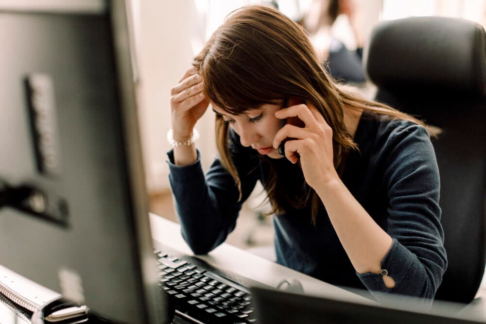 Computer programmer talking on phone at workplace