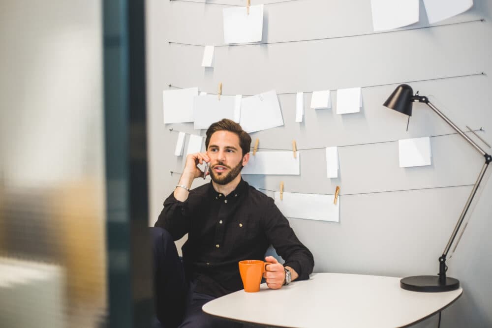 Creative businessman talking on mobile phone while sitting at desk in office